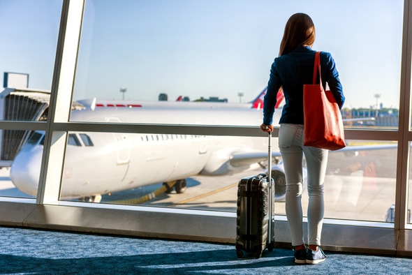 Imagem de uma menina no aeroporto com um mala, aparentemente esperando para viajar