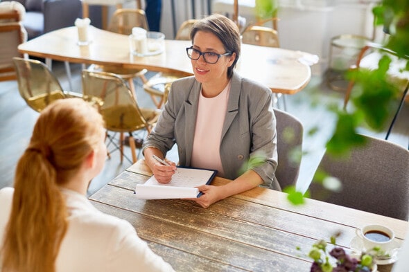 Imagem de uma entrevista de emprego. Tanto a entrevistadora quanto a entrevistada são mulheres.